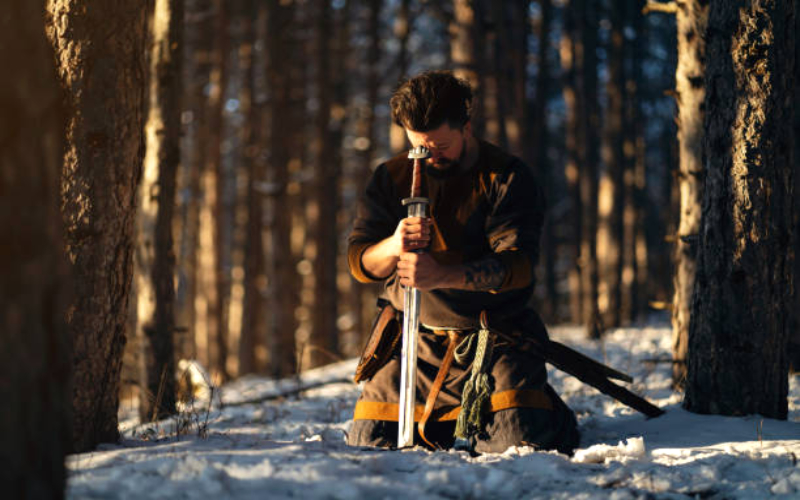Portrait of a medieval warrior kneeling in the forest while praying